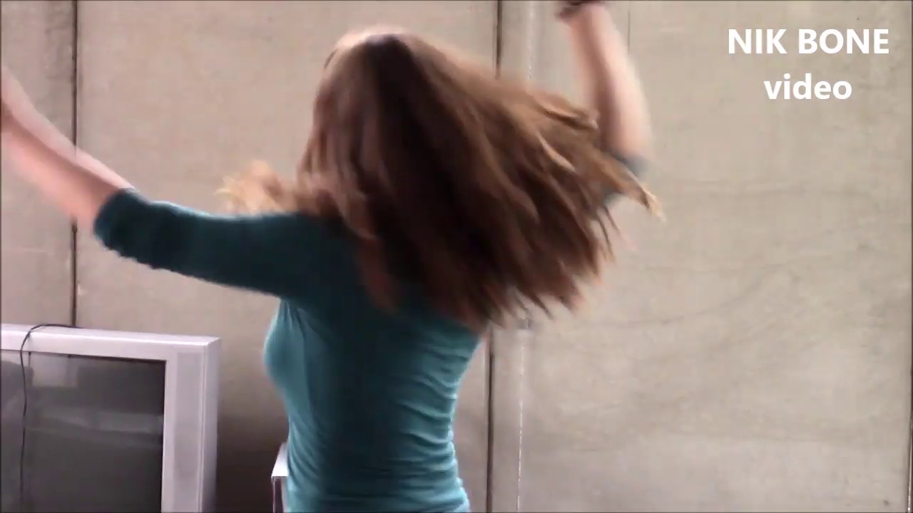 Bezaubernde Tänzerin trampelt auf einem Auto herum und macht Dellen rein