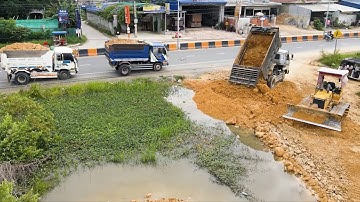 Nicely !! Dump truck unloading soil into pit and smart operator bulldozer working push landfilling 