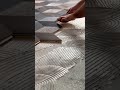 Installing wooden floor tiles in a geometric pattern over a layer of thick adhesive