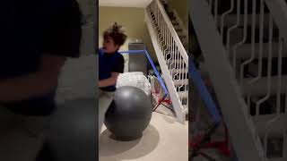 Boy jumps on exercise ball from handrail in basement then bounces onto fireplace