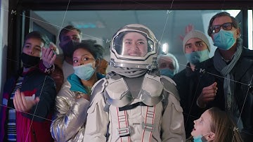 Asian woman in spacesuit in middle of crazy crowd during sale
