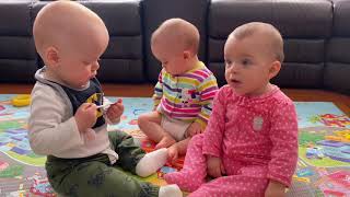 Triplets cute babies playing and fighting over pacifier