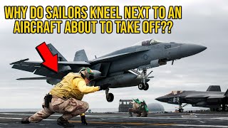 Why Navy Sailors Kneel Right Next To A Plane About To Take Off On An Aircraft Carrier