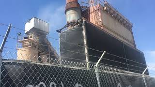 Unenclosed asphalt truck loading, in violation of a decades old legal settlement