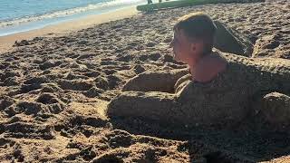 Brother Molds Boy Into a Sand Sphinx at the Seashore