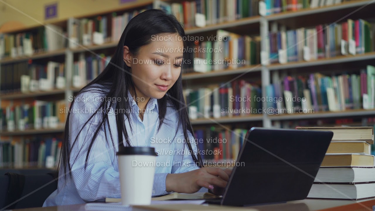 Young asian student girl sitting at table with pile of books in ...