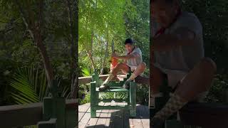 Guy holding beer bottle sits on green bench then falls back off balcony banister