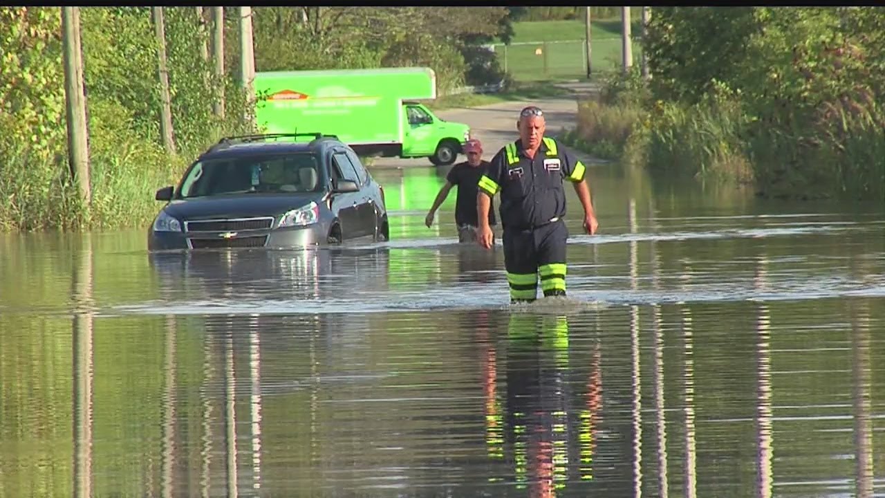 sharon white Tow truck driver helps elderly man out of car on flooded Warren road