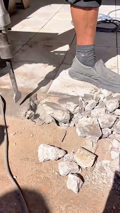 Breaking concrete with a powerful jackhammer.Construction work in progress to reshape the foundation