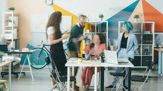 Zoom-out time lapse of young men and women working in creative office together