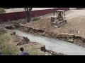 An Old Strong Komatsu Dozer Pushing Soil And Rock Filling Land With 25T Dump Trucks