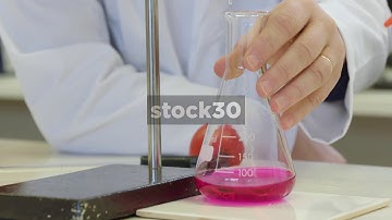 Slow Motion Shot Of Scientist Swirling Coloured Liquid In Conical Flask