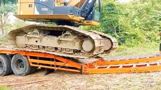 The process of lifting and lowering a Caterpillar excavator onto a selfloader.