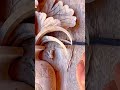 carving an intricate vase relief with fish and leaves pattern on a wooden board using sharp chisel