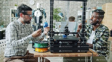 Slow motion of guys discussing 3d printing process in office watching equipment