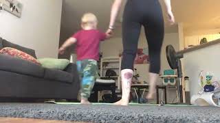 Mom exercises in the living room but son gets in the way