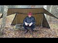 Under a tarp tent in the rain cooking burgers on a camping stove