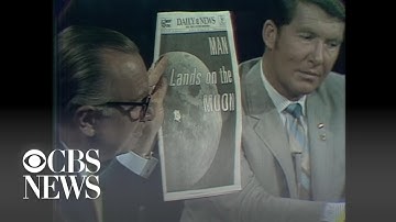 Walter Cronkite shows front-page headlines about moon landing