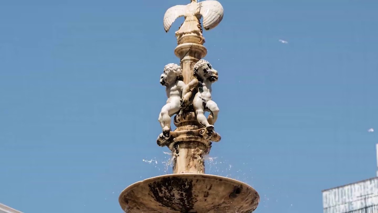 Fountain featuring cherubs and an eagle atop, symbolizing luxury and elegance, with a clear blue sky backdrop, relevant to Gran Hotel Miramar's promotion as a premier destination for meetings and incentives in Málaga.
