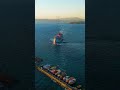 Vertical video. Kusadasi, Turkey. A boutique cruise ship departs from the pier at dusk, passing P...