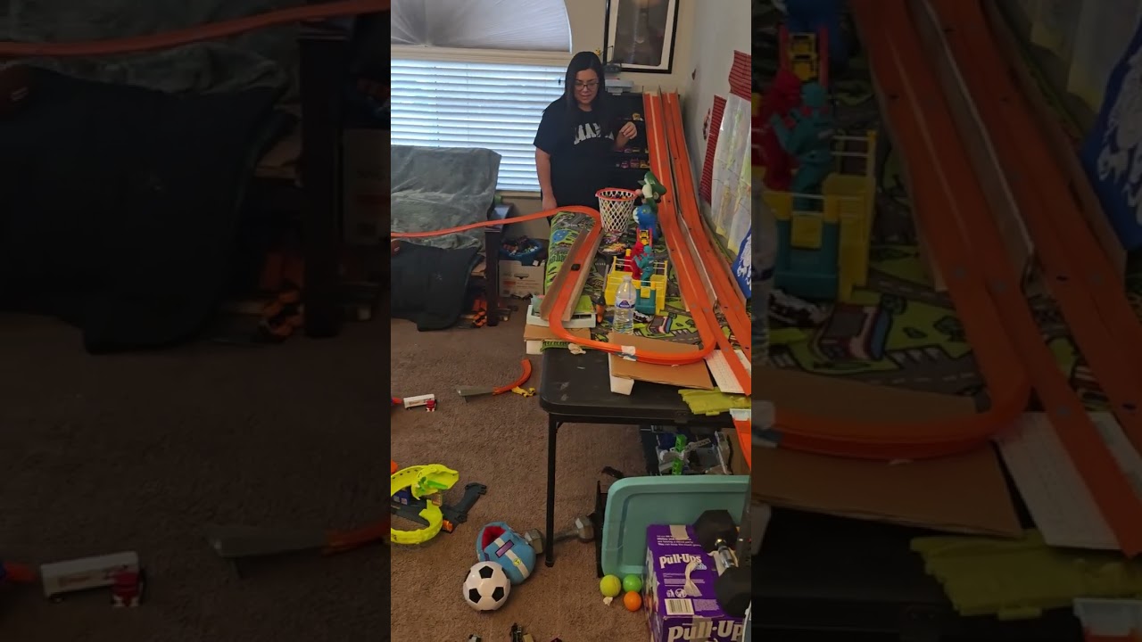 Guy sets up Hot Wheels Track around room then car hits boy on his face at the end
