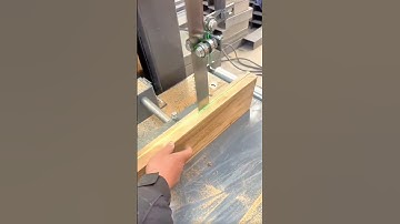 Guiding a wooden board through a vertical bandsaw to create a smooth precise straight cut