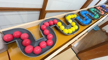 Marble run course using pipe ramps, a large wooden funnel, clear pipes, rain gutters, and iron balls