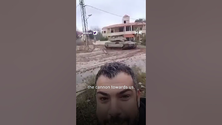 Lebanese man gives victory sign in front of Israeli tank during ceasefire