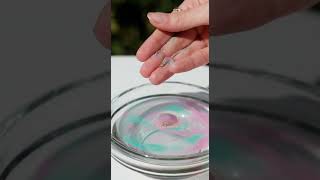 Hands placing colored sand in water as soft whispers guide deep breathing.