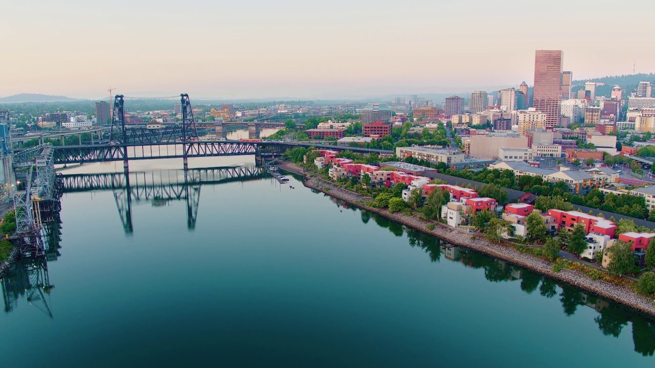 Drone aerial reveal of 2 trolley's crossing the Steel Bridge with flyover of Broadway Bridge and dow