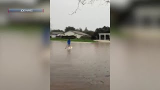 Man takes paddle board onto flooded lake in Goleta