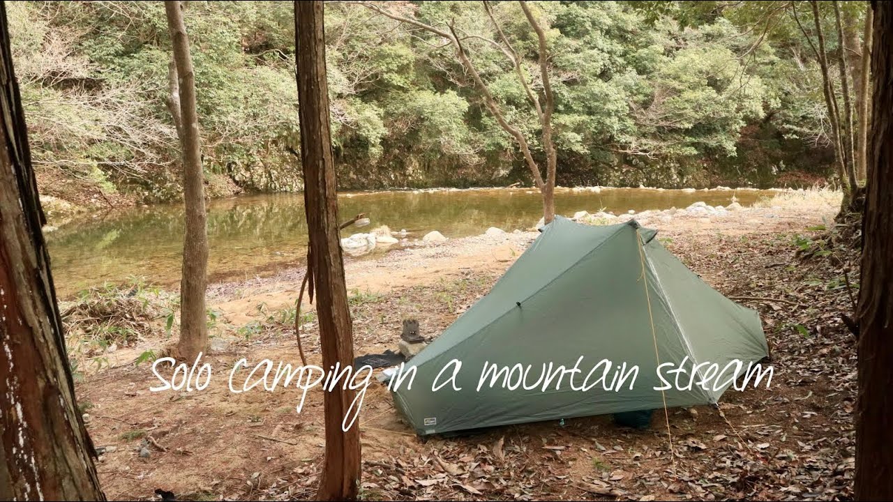 Solo camping in a quiet mountain stream with a tarp tent notch and 