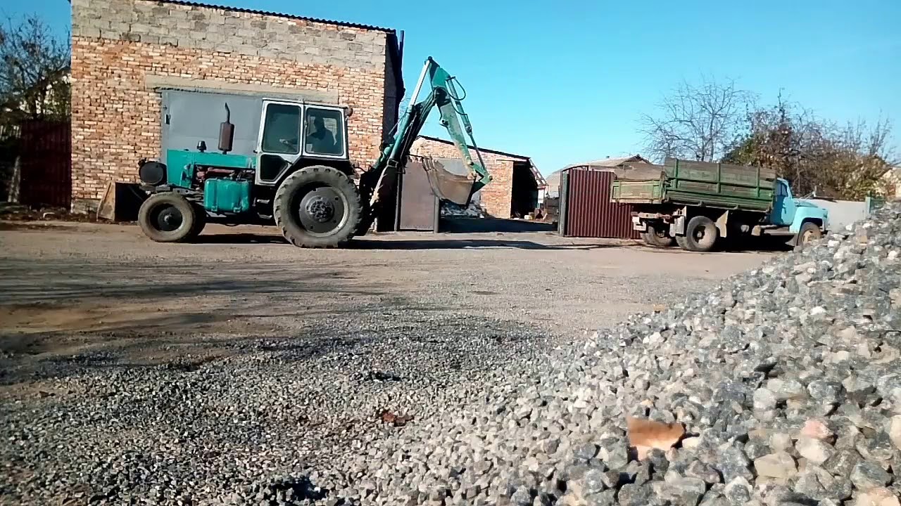 Камаз грузит трактор