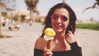 beautiful woman in sunglasses eating ice cream in the park with palm trees close up slow