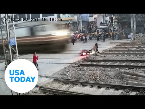 Lucky biker narrowly avoids being hit by train in northern India | USA TODAY