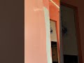 painting the white walls with a bright peach color using a long roller to refresh the room interior