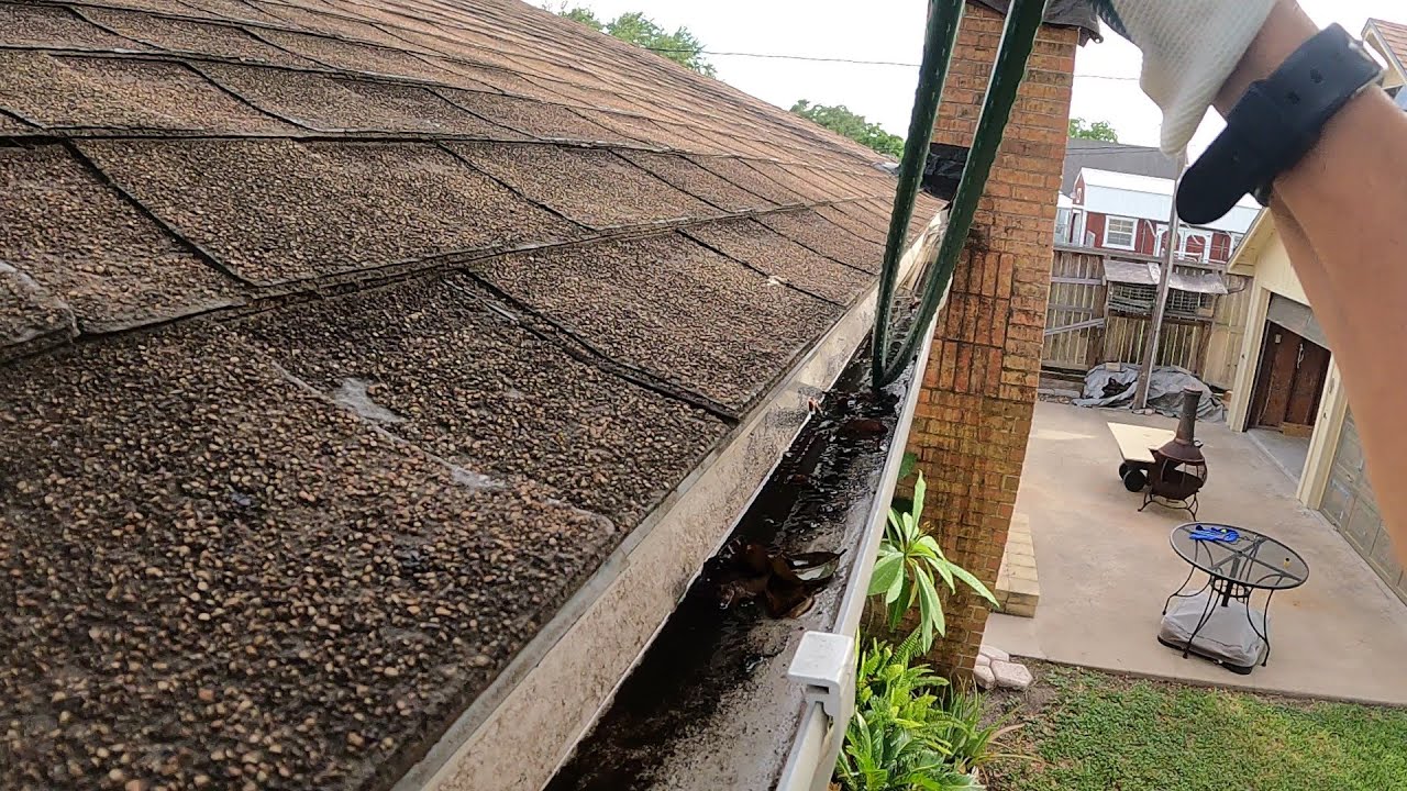 Cleaning out a gutter the hard way before it rains.