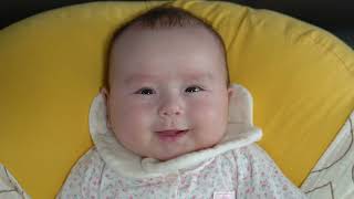 Cute baby girl lying on soft cushion looking and smiling at camera