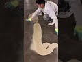Applying a smooth light beige floor coating with a metal spreader across a large grey indoor surface