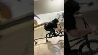 BMX rider grinds rail with pegs then falls back and bumps head at skatepark