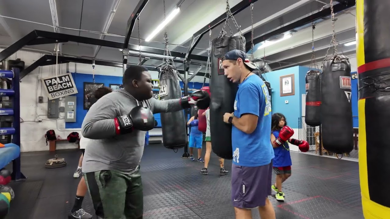 Coach Artem works with a youth boxing class student on making a wrist adjustment.