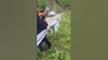 Workers are installing wavy guardrails on the steep slope of the mountain road