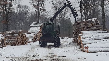John Deere forwarder unloading logs onto piles