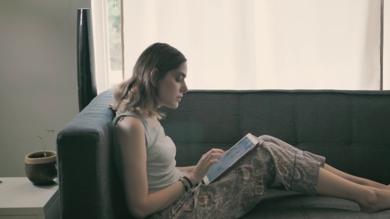 Young woman on her iPad lying on an armchair   Free Stock Video