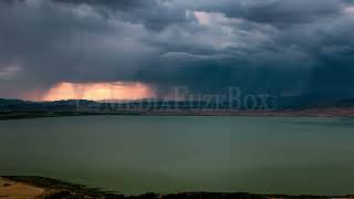 Stock Video - Dark storm clouds rolling over the landscape during colorful sunset