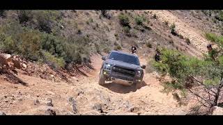 F150 Raptor climbing steep hill with sharp rocks