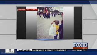 1st grader salutes flag during Mardi Gras parade
