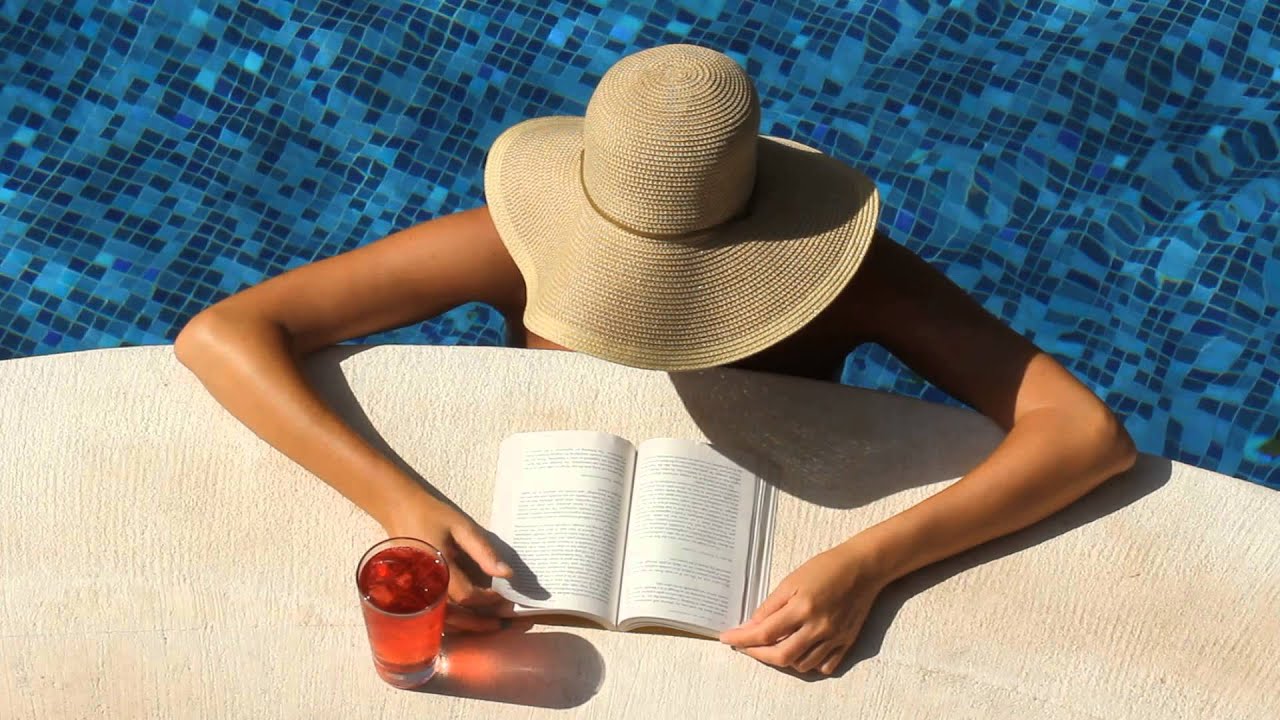 Шляпа современные нарезки. Солнце загар стоковое фото. Девушка в шляпе читает книгу крупный план простая одежда побережье.