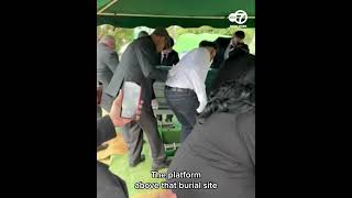 Pallbearers fall into grave