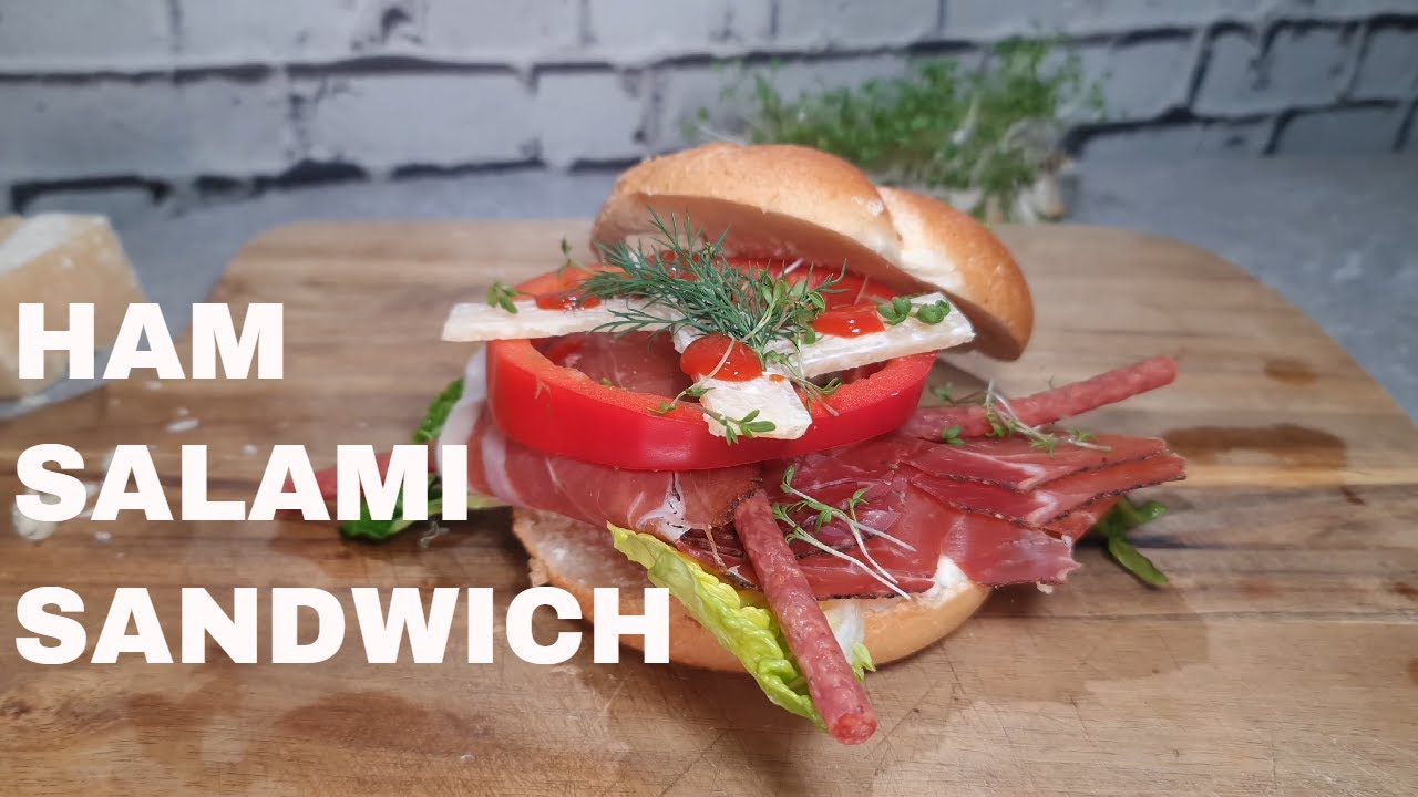 Sandwich with raw ham, salami sticks, parmesan, horseradish cream, lettuce, peppers, chili sauce